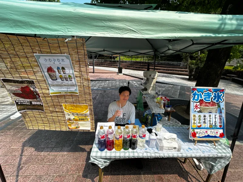 Pann at the shaved-ice stand under a tent at Beppu City Hall